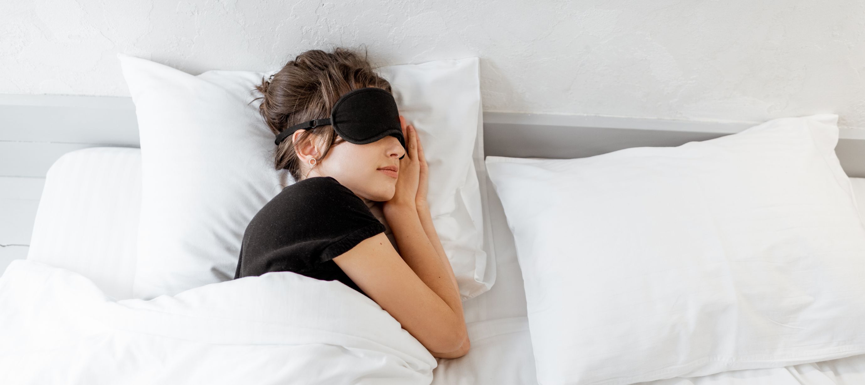 Žena ležící v posteli s maskou na očích