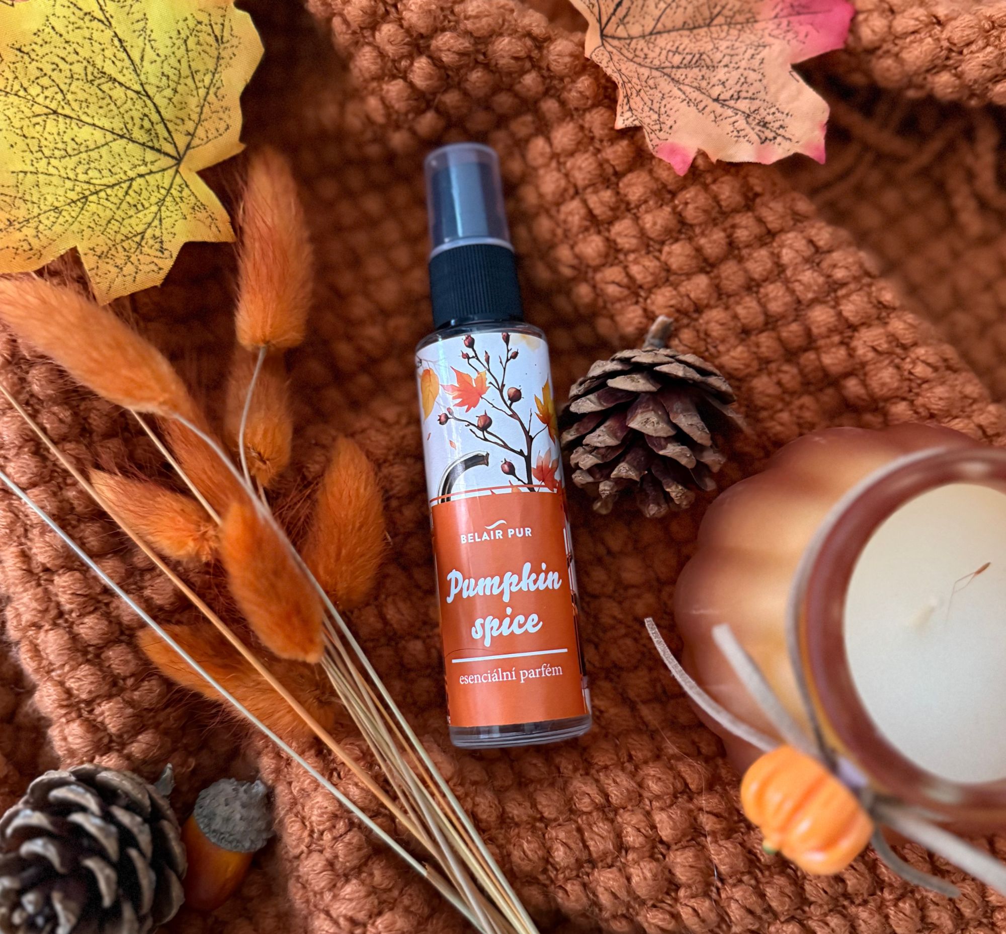 Esenciální parfém Pumpkin Spice ležící v podzimních dekoracích.