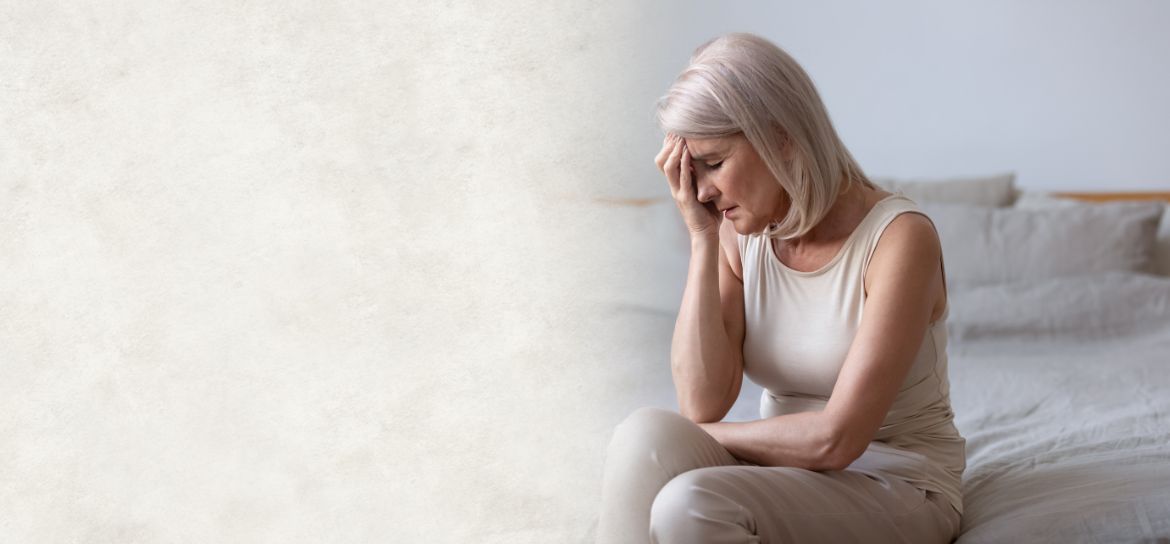 Žena sedící na posteli procházející menopauzou