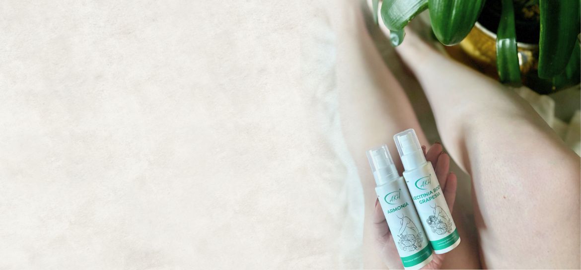 Ležící nohy na dece a ruka drží krémy na tělo.